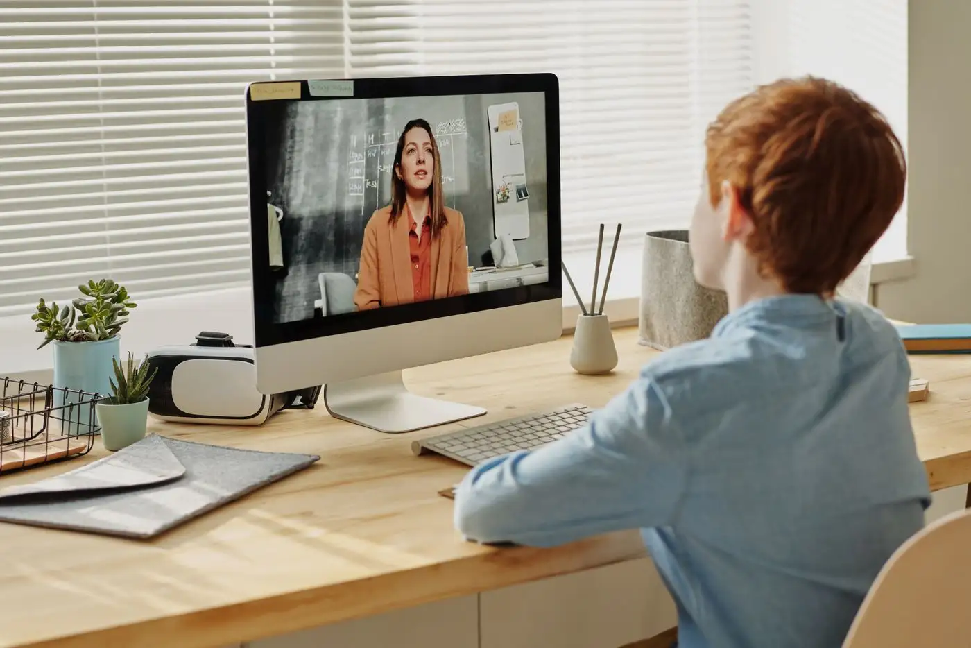 A person speaking to a colleague joining a live session on screen from a desk.