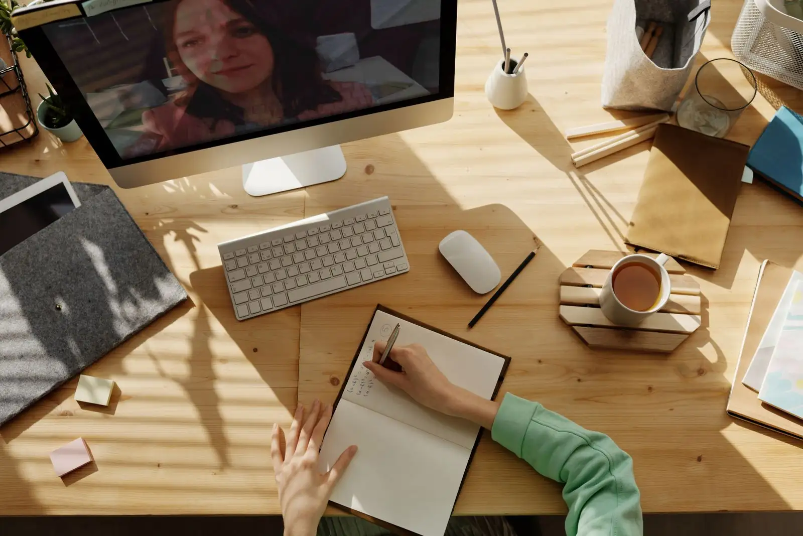 A desk seen from above with a notebook, pen and a live session open on screen.